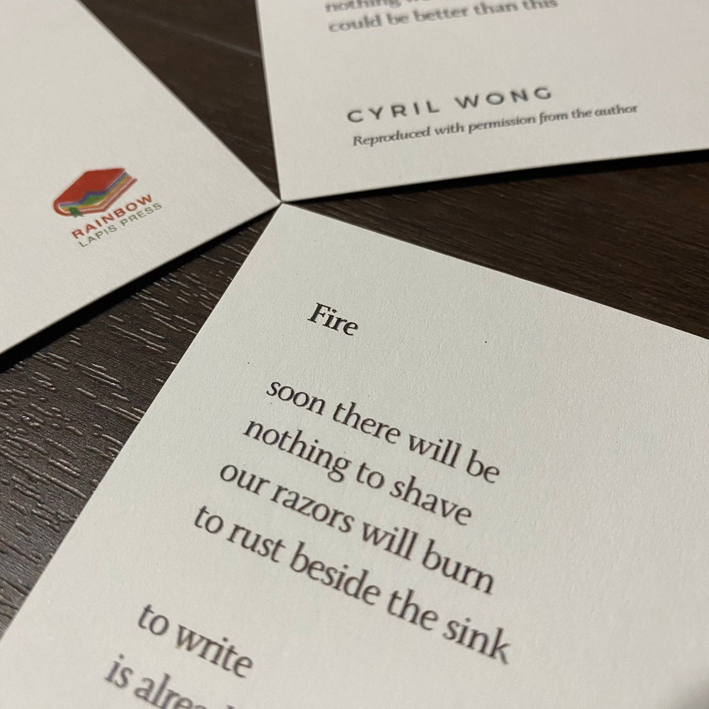 A5 postcard with the poem "Fire" by Cyril Wong printed on it, with the Rainbow Lapis Press logo on bottom right